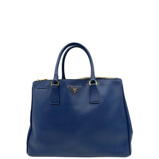 front Borsa Prada in pelle saffiano blu con parti metalliche dorate; munita di doppi manici stondati e impreziosita da una clochette portachiavi, di lusso, originale, ottime condizioni.