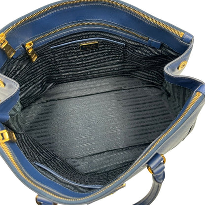 interno Borsa Prada in pelle saffiano blu con parti metalliche dorate; munita di doppi manici stondati e impreziosita da una clochette portachiavi, di lusso, originale, ottime condizioni. 