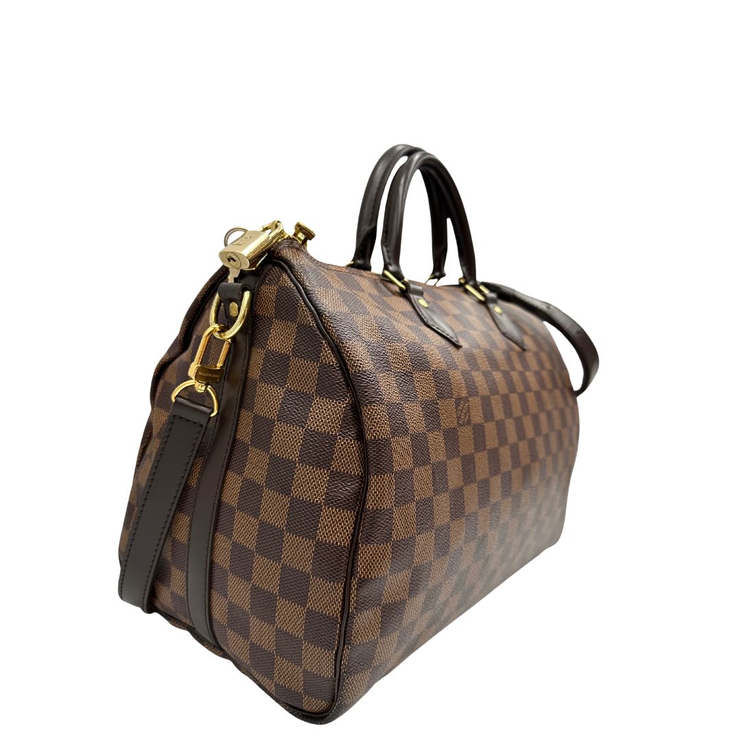 lato Borsa Speedy 35 in canvas Damier Ébène marrone con finiture in pelle marrone e parti metalliche dorate; munita di una tracolla amovibile e regolabile e doppi manici stondati. Completa di scatola, lucchetto e chiavi, di lusso, originale, usata. 