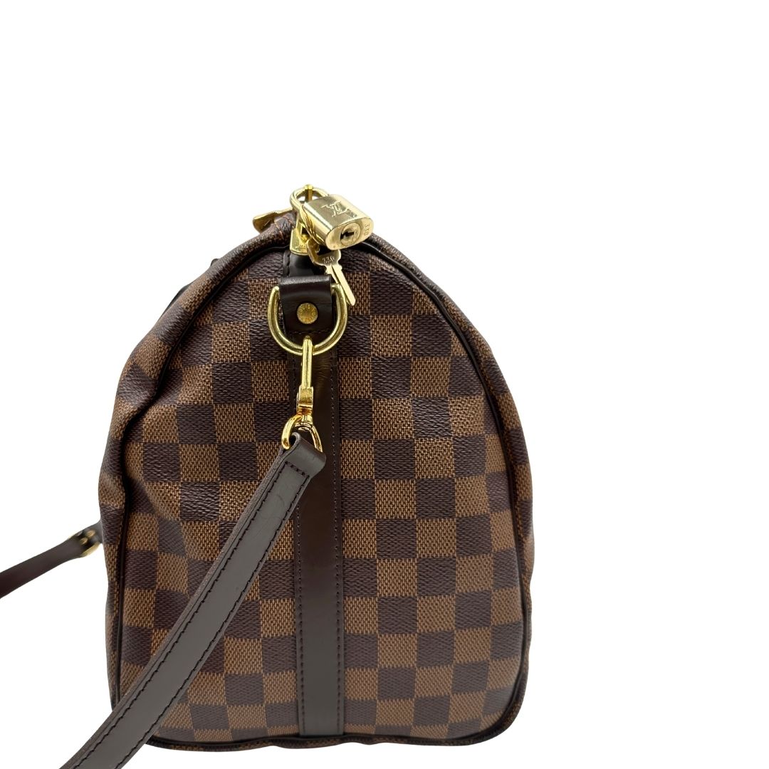 lato Borsa Speedy 35 in canvas Damier Ébène marrone con finiture in pelle marrone e parti metalliche dorate; munita di una tracolla amovibile e regolabile e doppi manici stondati. Completa di scatola, lucchetto e chiavi, di lusso, originale, usata. 