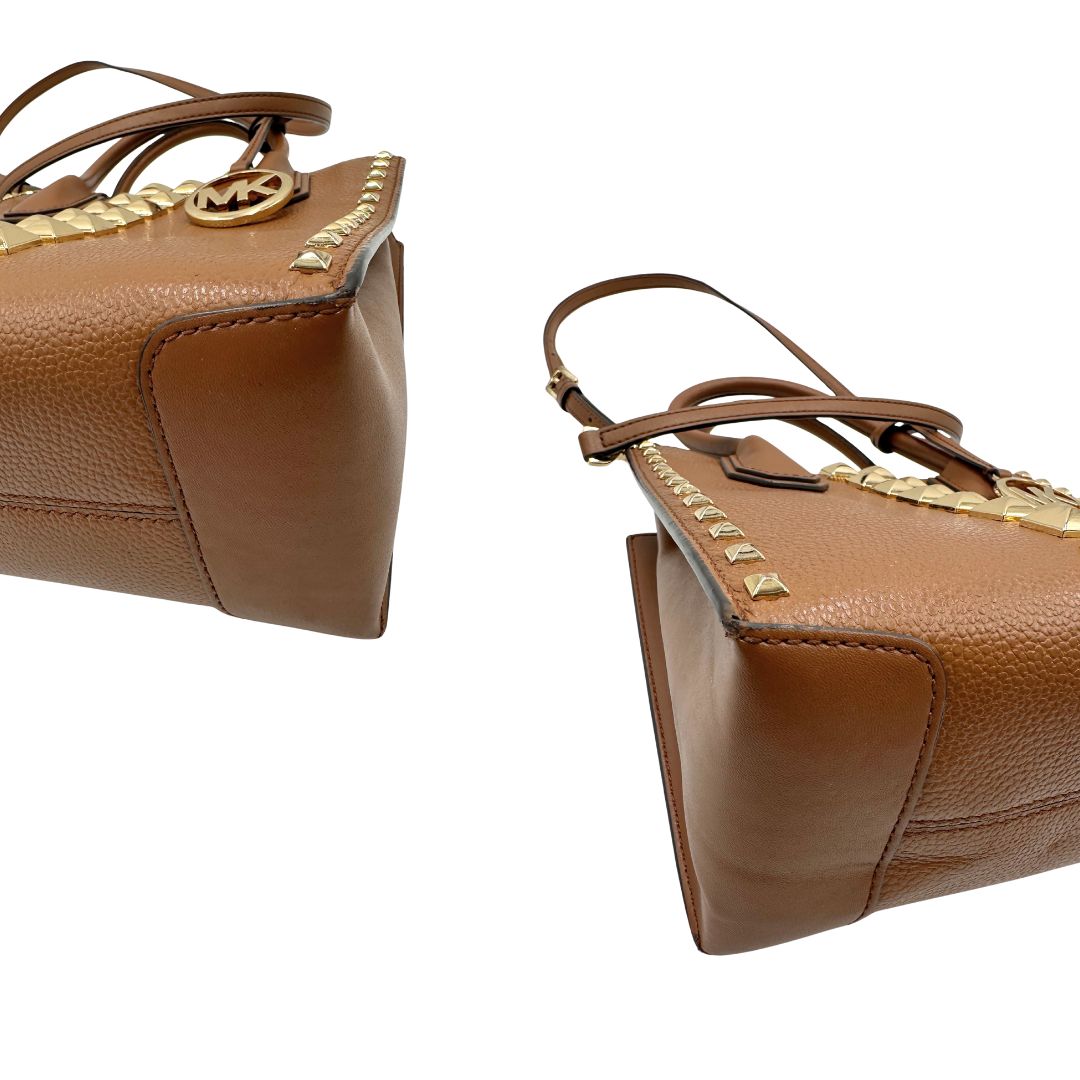 angoli Borsa Michael Kors in pelle color cammello con parti metalliche dorate; munita di doppi manici e una tracolla amovibile e regolabile, impreziosita da borchie piramidali, di lusso, originale, ottime condizioni.