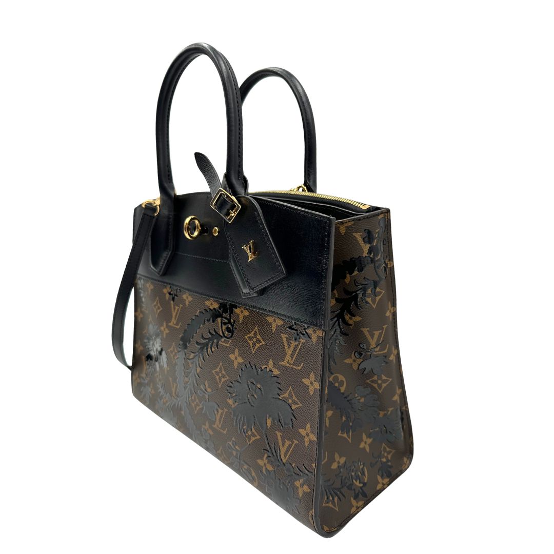 lato Borsa Louis Vuitton L.E. in canvas marrone monogram con finiture in pelle nera e parti metalliche dorate, impreziosita da motivo decorativo floreale verniciato nero e un porta address amovibile; munita di doppi manici stondati e una tracolla amovibile. Completa di dustbag, di lusso, originale, ottime condizioni. 