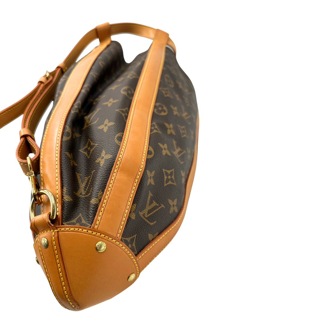 Angolo di un Zaino Louis Vuitton in canvas marrone monogram con finiture in vacchetta naturale e parti metalliche dorate; munita di un cinturino centrale con fibbia e un manico amovibili. Indossabile a spalla. Completa di dustbag. Originale, usata, di lusso, in ottime condizioni.