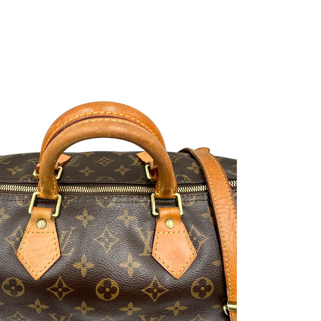 Manici di una Borsa Speedy 35 in canvas marrone monogram con finiture in vacchetta naturale e parti metalliche dorate; munita di doppi manici stondati e una tracolla amovibile e regolabile. Completa di lucchetto e chiavi. Originale, usato, di lusso, in ottime condizioni.