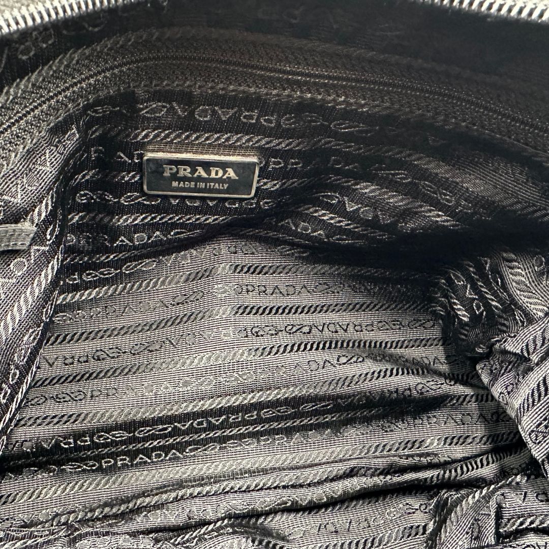 interno Borsa Prada in nylon nero con finiture in pelle tono su tono e parti metalliche argentate; munita di una tracolla regolabile in tessuto, di lusso, originale, ottime condizioni, usata.