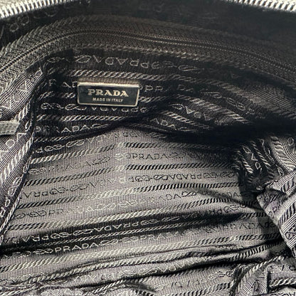 interno Borsa Prada in nylon nero con finiture in pelle tono su tono e parti metalliche argentate; munita di una tracolla regolabile in tessuto, di lusso, originale, ottime condizioni, usata.