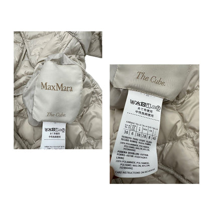 Piumino Max Mara The Cube in 100% poliammide trapuntato, colore avorio perla. Modello con cappuccio, coulisse regolabile in vita e dettagli metallici dorati. Chiusura con zip.