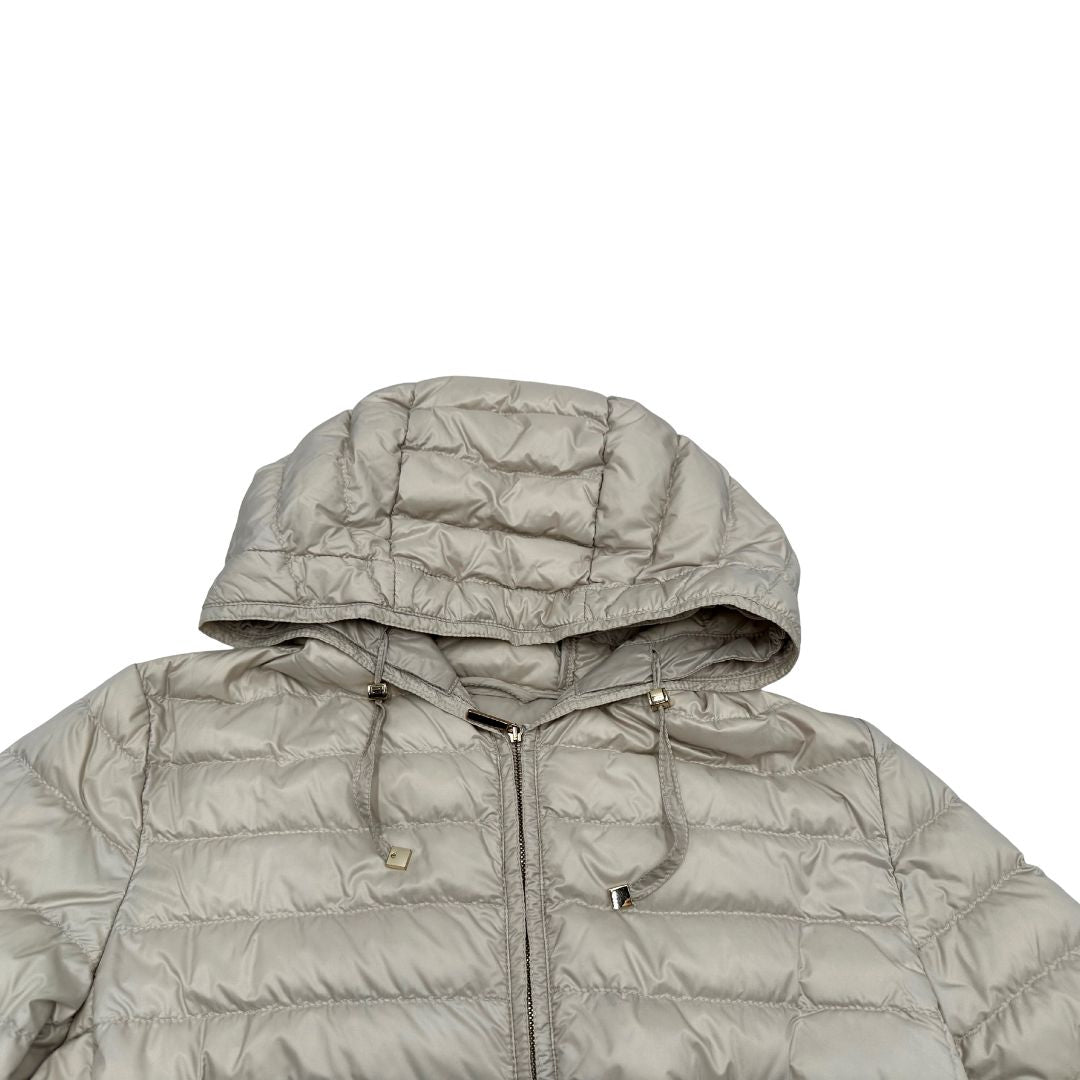 Piumino Max Mara The Cube in 100% poliammide trapuntato, colore avorio perla. Modello con cappuccio, coulisse regolabile in vita e dettagli metallici dorati. Chiusura con zip.