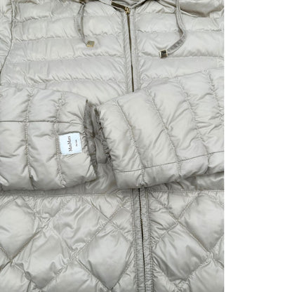 Piumino Max Mara The Cube in 100% poliammide trapuntato, colore avorio perla. Modello con cappuccio, coulisse regolabile in vita e dettagli metallici dorati. Chiusura con zip.