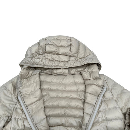 Piumino Max Mara The Cube in 100% poliammide trapuntato, colore avorio perla. Modello con cappuccio, coulisse regolabile in vita e dettagli metallici dorati. Chiusura con zip.