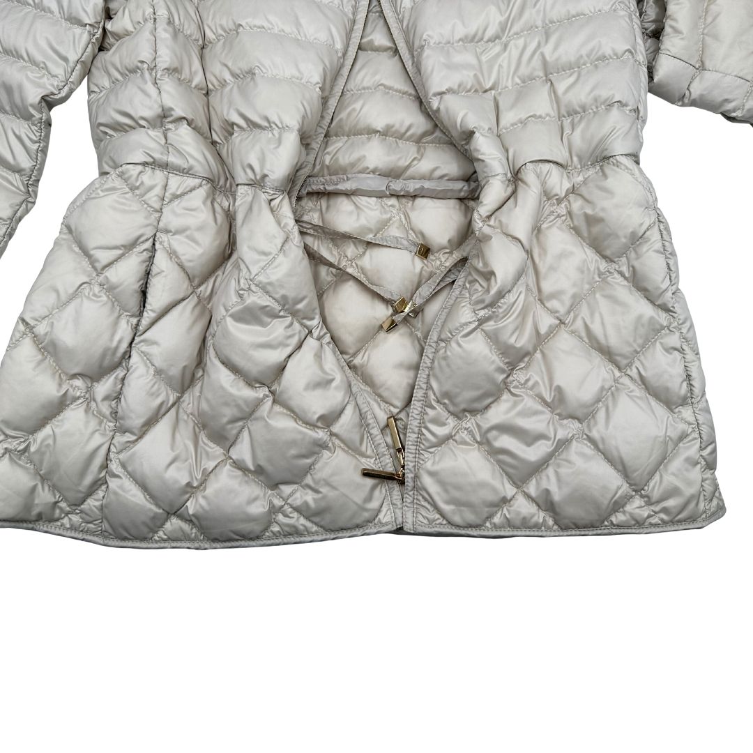 Piumino Max Mara The Cube in 100% poliammide trapuntato, colore avorio perla. Modello con cappuccio, coulisse regolabile in vita e dettagli metallici dorati. Chiusura con zip.