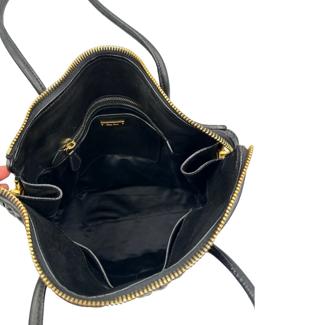 Interno di una Borsa Miu Miu realizzata in pelle goffrata nera con parti metalliche dorate; munita di due manici stondati, indossabile a spalla. Originale,, usata, di lusso, in ottime condizioni.