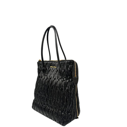 Lato sinistro di una Borsa Miu Miu realizzata in pelle goffrata nera con parti metalliche dorate; munita di due manici stondati, indossabile a spalla. Originale,, usata, di lusso, in ottime condizioni.