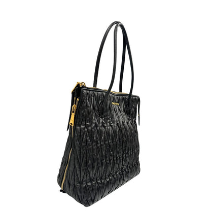 Lato destro di un Borsa Miu Miu realizzata in pelle goffrata nera con parti metalliche dorate; munita di due manici stondati, indossabile a spalla. Originale,, usata, di lusso, in ottime condizioni.