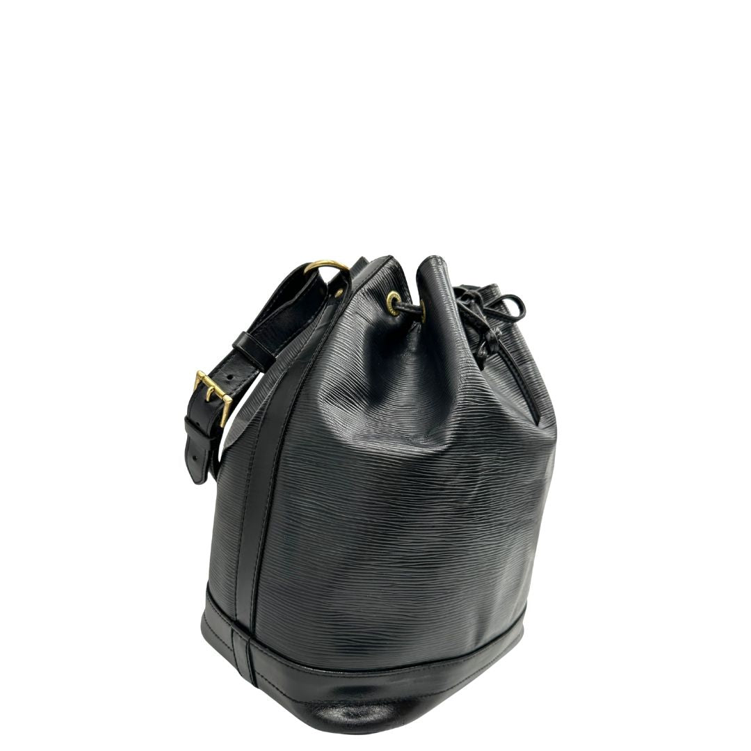 Laterale sinistro di un secchiello Noé Louis Vuitton in pelle Epi nera, con parti metalliche dorate e manico regolabile con fibbia. Indossabile a spalla. Completa di dustbag.