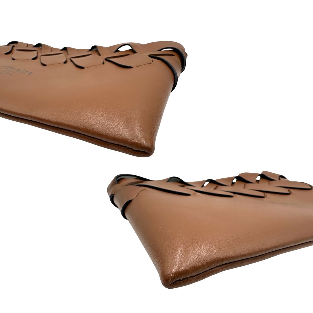 Angoli di una Pochette Prada in pelle marrone cognac con parti metalliche argentate, presenta un motivo intrecciato nella parte superiore, munita di una pochette estraibile in pelle nera con logo lettering sul front. Originale, usata, di lusso, in ottime condizioni.