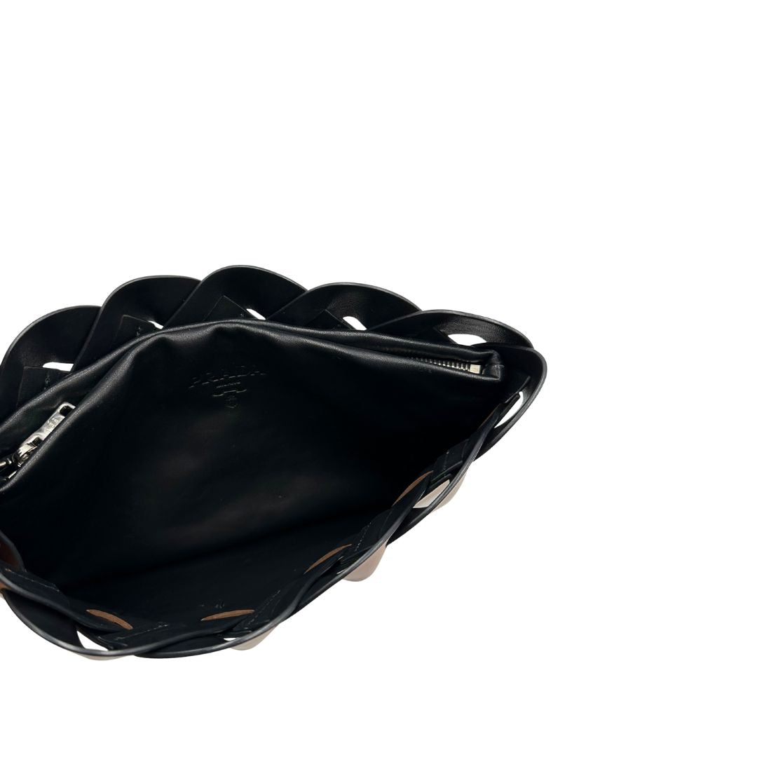 Interno di una Pochette Prada in pelle marrone cognac con parti metalliche argentate, presenta un motivo intrecciato nella parte superiore, munita di una pochette estraibile in pelle nera con logo lettering sul front. Originale, usata, di lusso, in ottime condizioni.