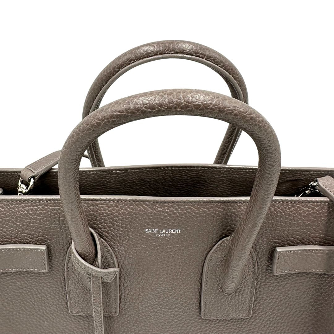 manici Borsa Saint Laurent in pelle martellata grigia con parti metalliche argentate; munita di doppi manici stondati e una tracolla amovibile. Impreziosita da un lucchetto decorativo, di lusso, originale, ottime condizioni.