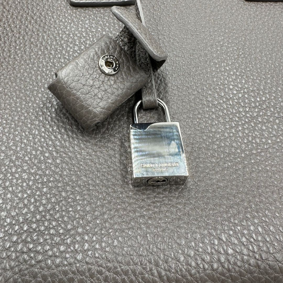 lucchetto Borsa Saint Laurent in pelle martellata grigia con parti metalliche argentate; munita di doppi manici stondati e una tracolla amovibile. Impreziosita da un lucchetto decorativo, di lusso, originale, ottime condizioni. 