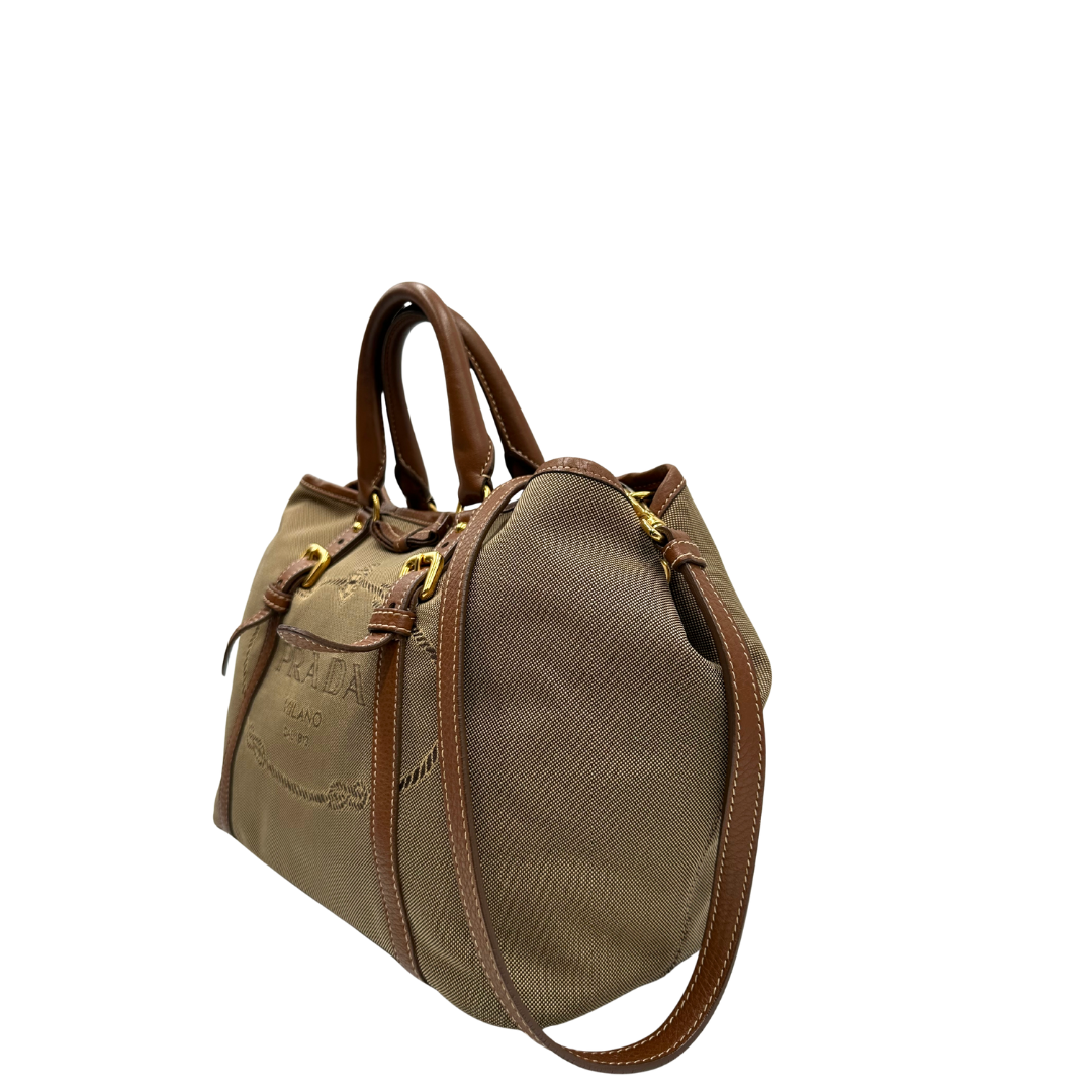 lato  Borsa Prada in tessuto Jacquard, finiture in pelle marroni e parti metalliche dorate; munita di doppi manici e una tracolla amovibile e regolabile. Completa di dustbag, di lusso, originale, ottime condizioni. 