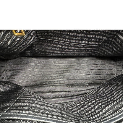 Interno di una borsa Prada in pelle saffiano nera con parti metalliche dorate, munita di doppi manici stondati, tracolla amovibile e regolabile ed una clochette portachiavi. Completa di dustbag