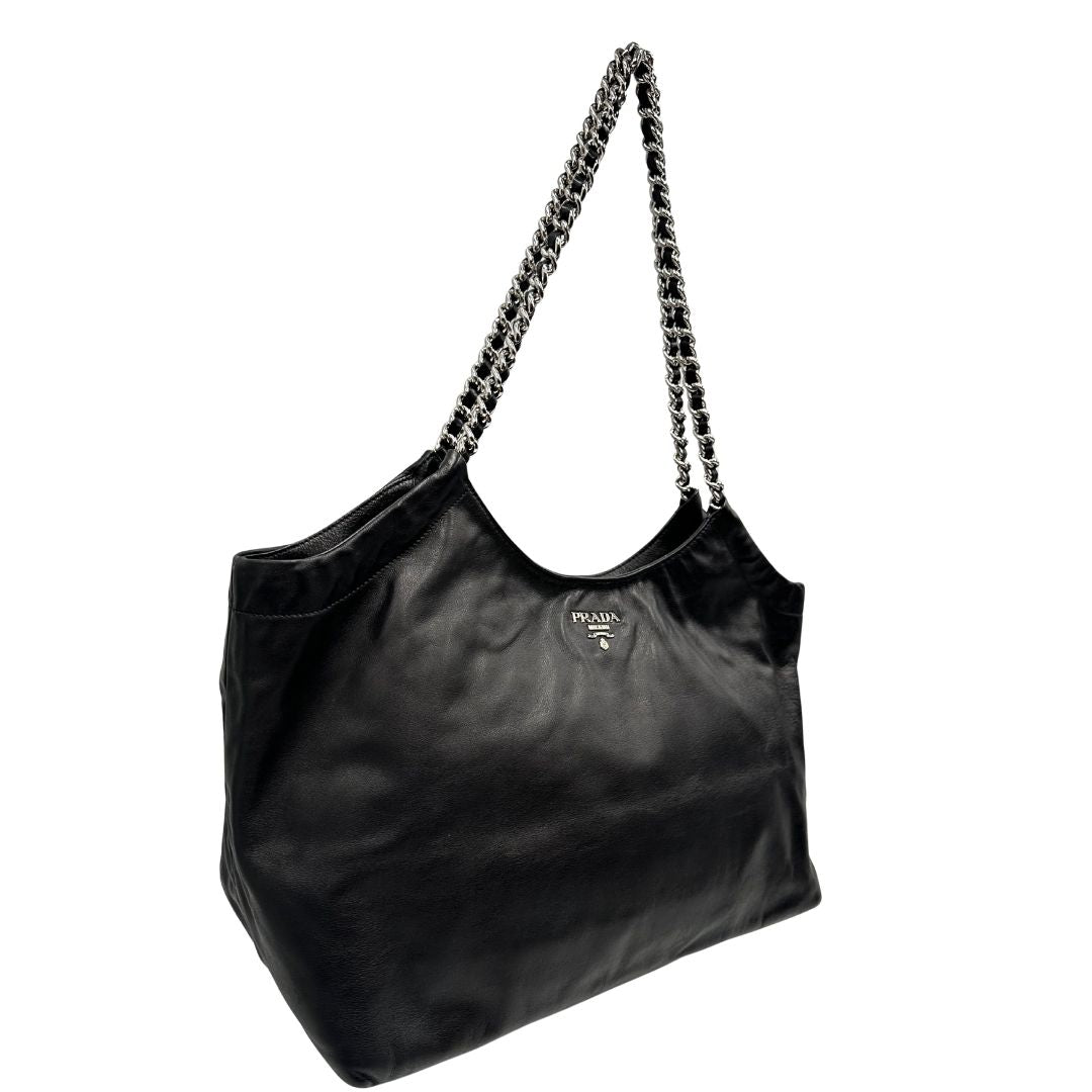 lato Borsa Prada in pelle nera con parti metalliche argentate; munita di doppi manici in pelle e catena intrecciati, da portare a spalla, di lusso, originale, ottime condizioni, usata.