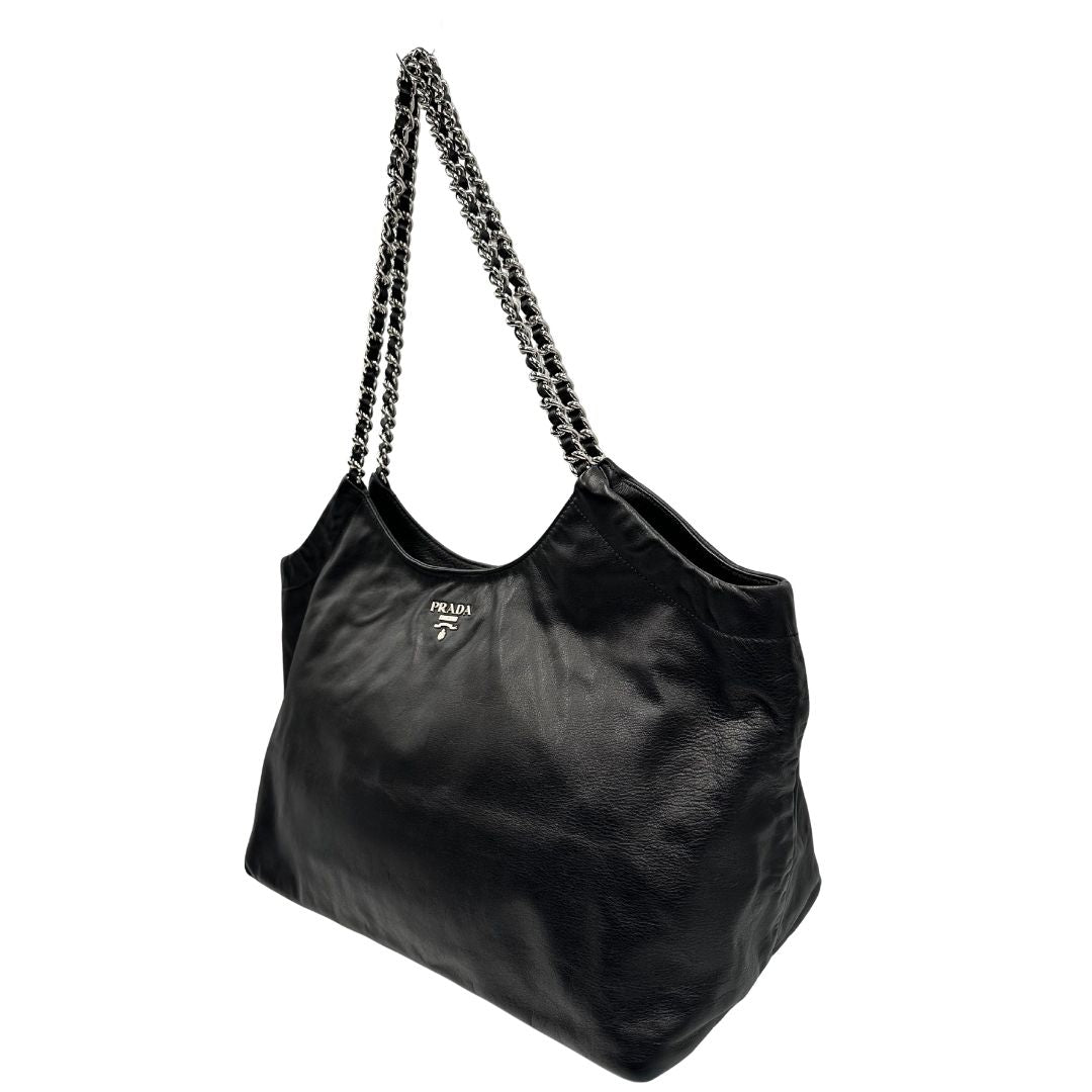 lato Borsa Prada in pelle nera con parti metalliche argentate; munita di doppi manici in pelle e catena intrecciati, da portare a spalla, di lusso, originale, ottime condizioni, usata.