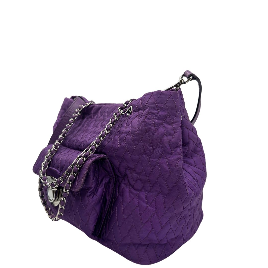lato Borsa Prada in nylon viola con finiture in pelle tono su tono e parti metalliche argentate; munita di doppi manici in catena e pelle intrecciati e una tracolla amovibile e regolabile. Completa di dustbag, di lusso, originale, ottime condizioni, usata, originale. 