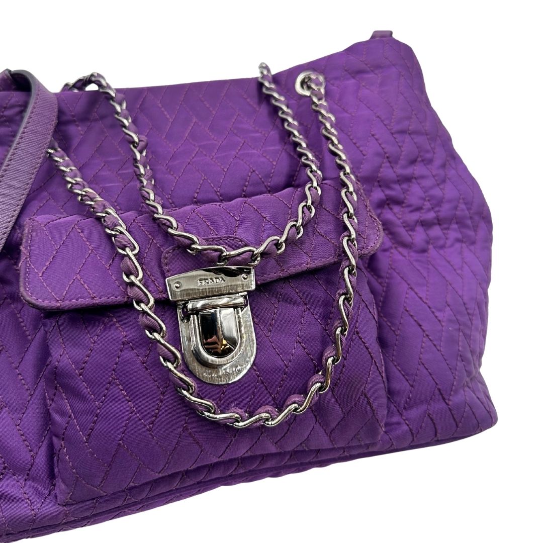 Borsa Prada in nylon viola con finiture in pelle tono su tono e parti metalliche argentate; munita di doppi manici in catena e pelle intrecciati e una tracolla amovibile e regolabile. Completa di dustbag, di lusso, originale, ottime condizioni, usata, originale. 