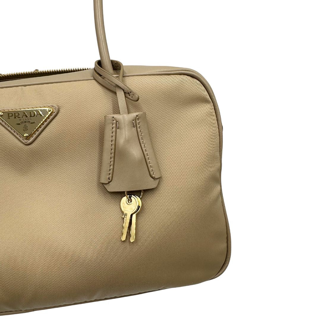 Borsa Prada in nylon beige con finiture in pelle tono su tono e parti metalliche dorate; munita di doppi manici sottili e stondati, indossabile a spalla. Completa di chiavi, lucchetto, cartellini e dustbag, di lusso, originale, ottime condizioni.  