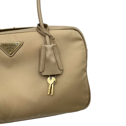 Borsa Prada in nylon beige con finiture in pelle tono su tono e parti metalliche dorate; munita di doppi manici sottili e stondati, indossabile a spalla. Completa di chiavi, lucchetto, cartellini e dustbag, di lusso, originale, ottime condizioni.  