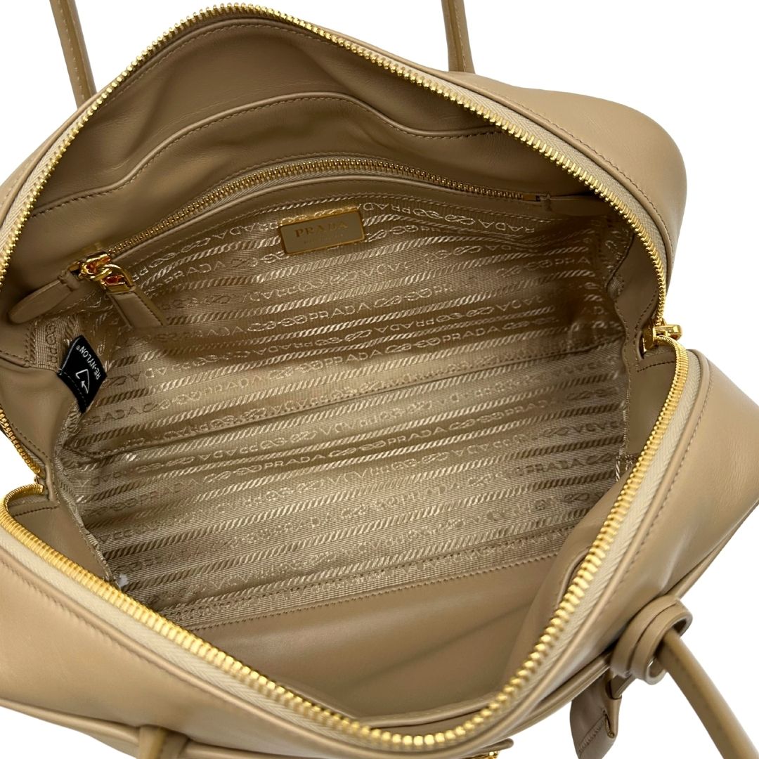 interno della Borsa Prada in nylon beige con finiture in pelle tono su tono e parti metalliche dorate; munita di doppi manici sottili e stondati, indossabile a spalla. Completa di chiavi, lucchetto, cartellini e dustbag, di lusso, originale, ottime condizioni.  