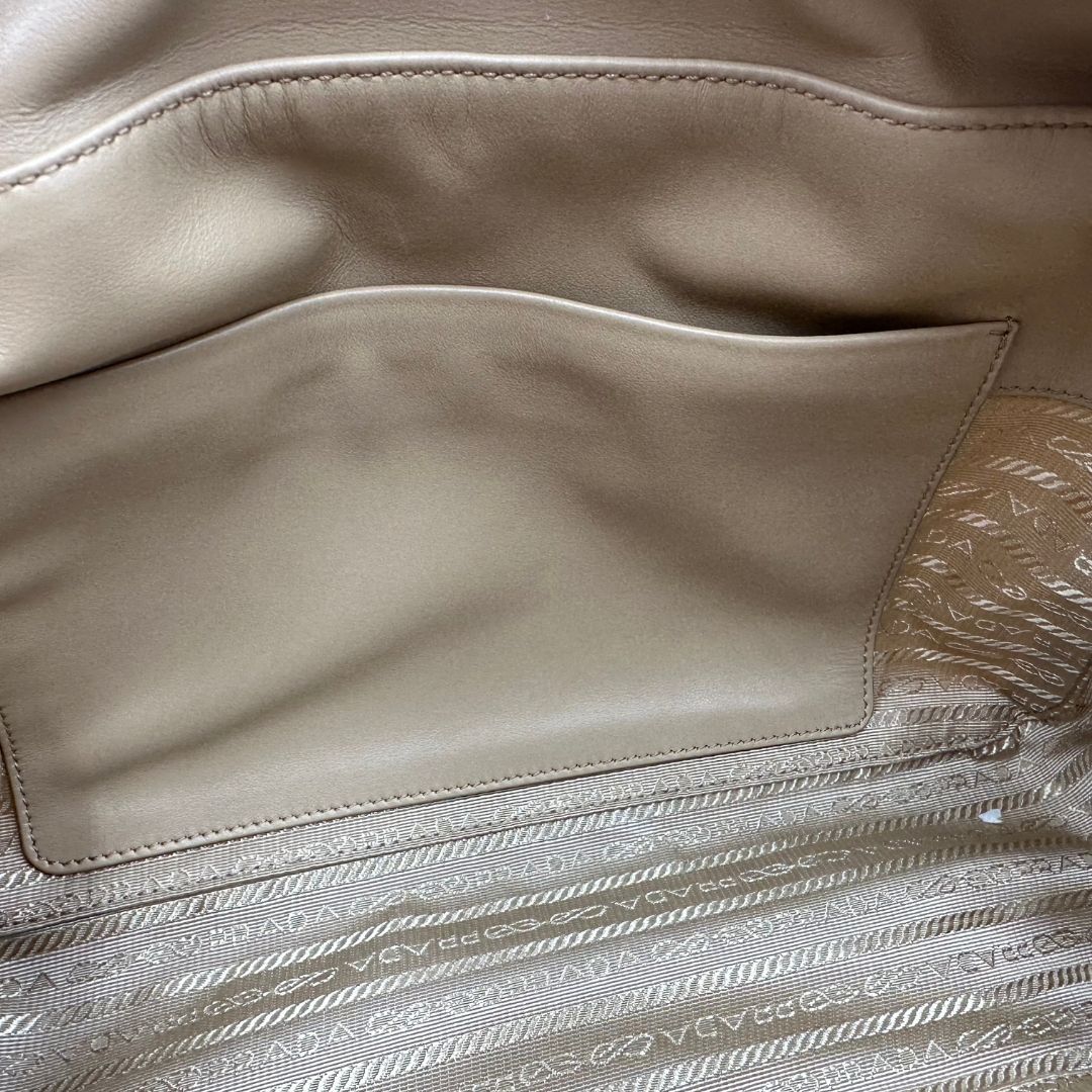 interno della Borsa Prada in nylon beige con finiture in pelle tono su tono e parti metalliche dorate; munita di doppi manici sottili e stondati, indossabile a spalla. Completa di chiavi, lucchetto, cartellini e dustbag, di lusso, originale, ottime condizioni.  