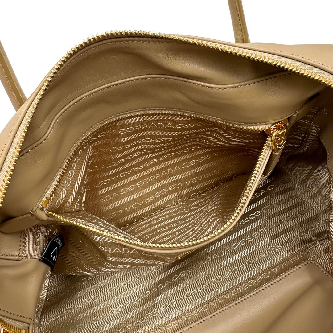 interno della Borsa Prada in nylon beige con finiture in pelle tono su tono e parti metalliche dorate; munita di doppi manici sottili e stondati, indossabile a spalla. Completa di chiavi, lucchetto, cartellini e dustbag, di lusso, originale, ottime condizioni.  