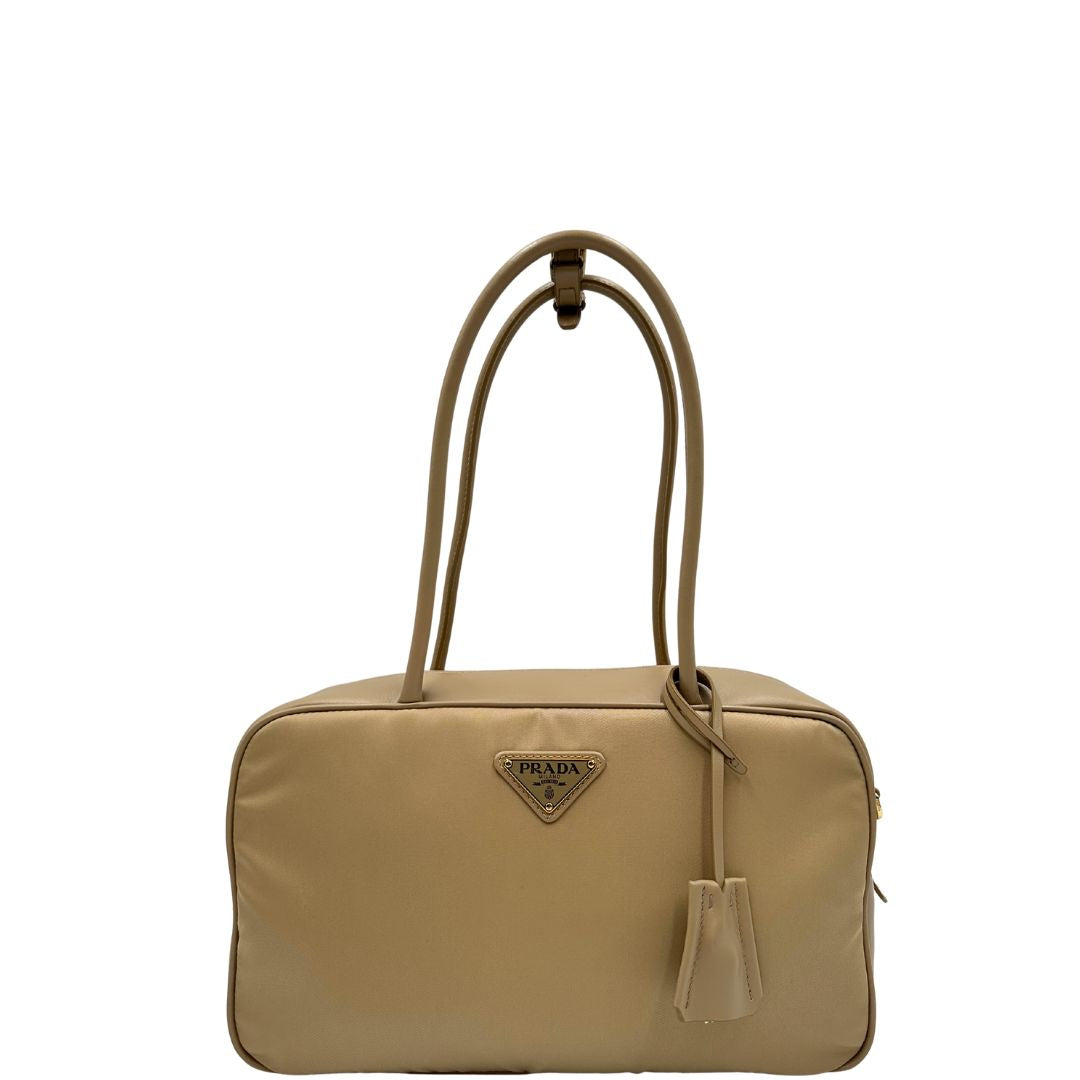 front Borsa Prada in nylon beige con finiture in pelle tono su tono e parti metalliche dorate; munita di doppi manici sottili e stondati, indossabile a spalla. Completa di chiavi, lucchetto, cartellini e dustbag, di lusso, originale, ottime condizioni. 