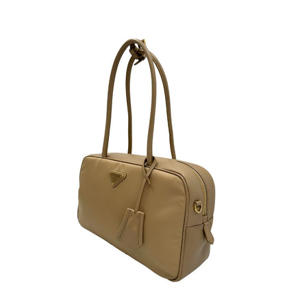 lato Borsa Prada in nylon beige con finiture in pelle tono su tono e parti metalliche dorate; munita di doppi manici sottili e stondati, indossabile a spalla. Completa di chiavi, lucchetto, cartellini e dustbag, di lusso, originale, ottime condizioni.  
