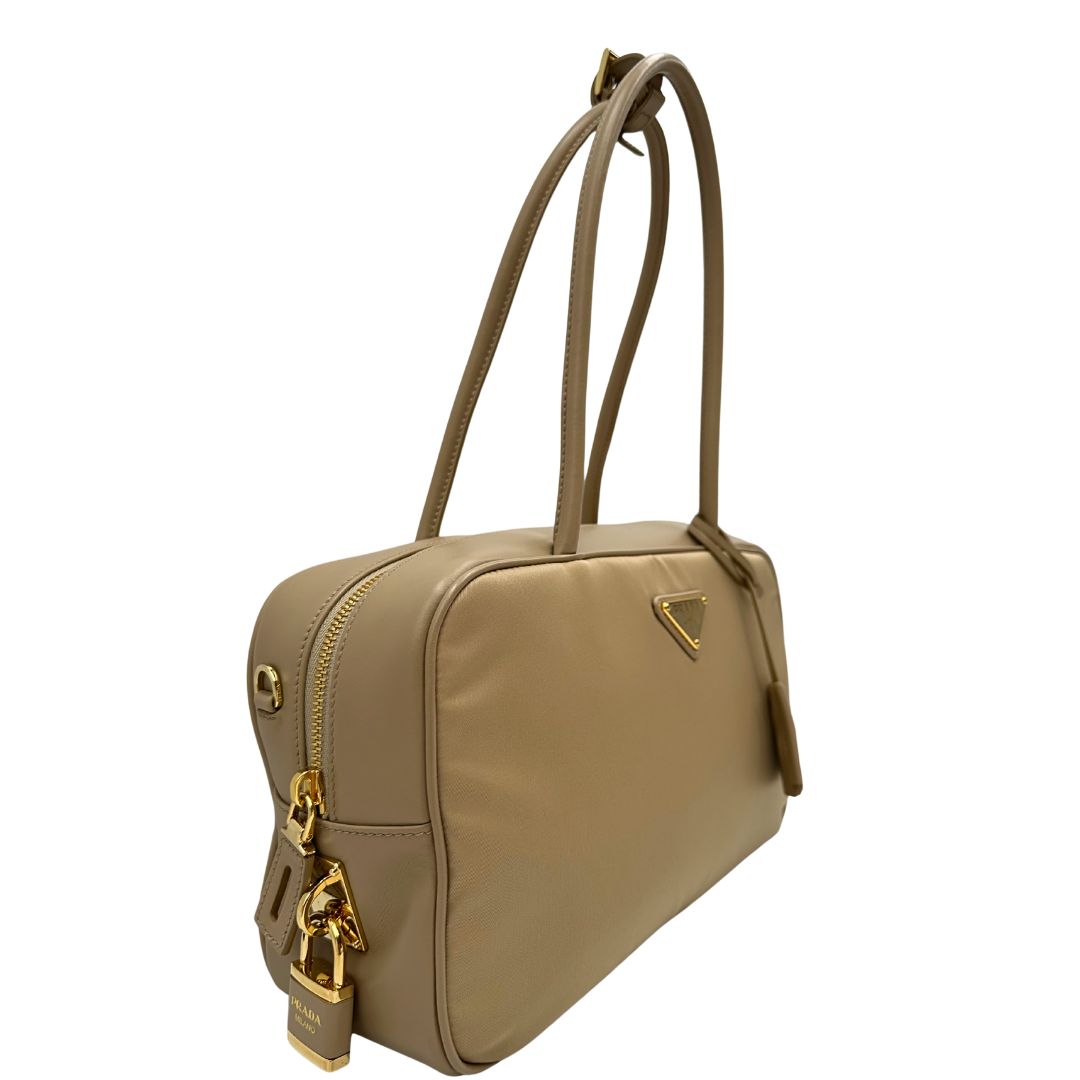 lato Borsa Prada in nylon beige con finiture in pelle tono su tono e parti metalliche dorate; munita di doppi manici sottili e stondati, indossabile a spalla. Completa di chiavi, lucchetto, cartellini e dustbag, di lusso, originale, ottime condizioni. 