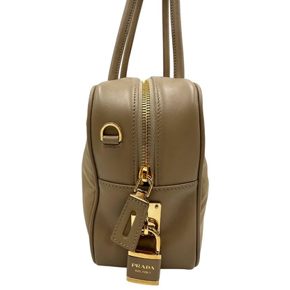 lato Borsa Prada in nylon beige con finiture in pelle tono su tono e parti metalliche dorate; munita di doppi manici sottili e stondati, indossabile a spalla. Completa di chiavi, lucchetto, cartellini e dustbag, di lusso, originale, ottime condizioni.  