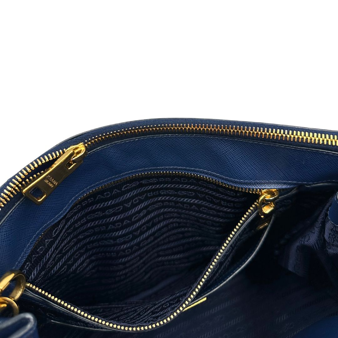 interno Borsa Prada in pelle saffiano blu con parti metalliche dorate; munita di doppi manici stondati, una tracolla amovibile e regolabile e impreziosita da un portachiavi, usata, originale, ottime condizioni. 