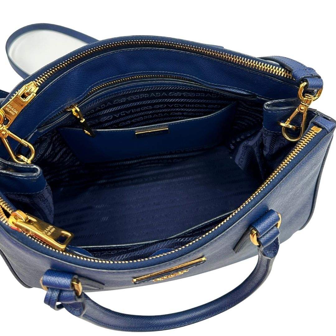 interno Borsa Prada in pelle saffiano blu con parti metalliche dorate; munita di doppi manici stondati, una tracolla amovibile e regolabile e impreziosita da un portachiavi, usata, originale, ottime condizioni.