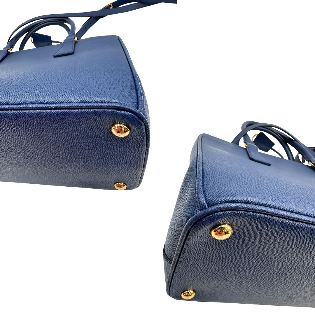 angoli Borsa Prada in pelle saffiano blu con parti metalliche dorate; munita di doppi manici stondati, una tracolla amovibile e regolabile e impreziosita da un portachiavi, usata, originale, ottime condizioni.
