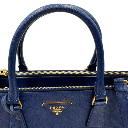 manici Borsa Prada in pelle saffiano blu con parti metalliche dorate; munita di doppi manici stondati, una tracolla amovibile e regolabile e impreziosita da un portachiavi, usata, originale, ottime condizioni.
