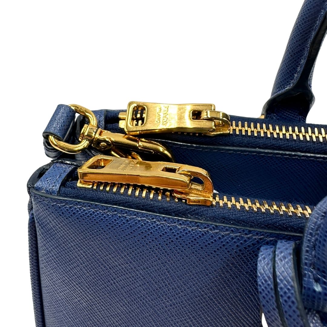 cerniera Borsa Prada in pelle saffiano blu con parti metalliche dorate; munita di doppi manici stondati, una tracolla amovibile e regolabile e impreziosita da un portachiavi, usata, originale, ottime condizioni. 