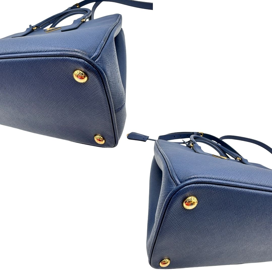 angoli Borsa Prada in pelle saffiano blu con parti metalliche dorate; munita di doppi manici stondati, una tracolla amovibile e regolabile e impreziosita da un portachiavi, usata, originale, ottime condizioni.