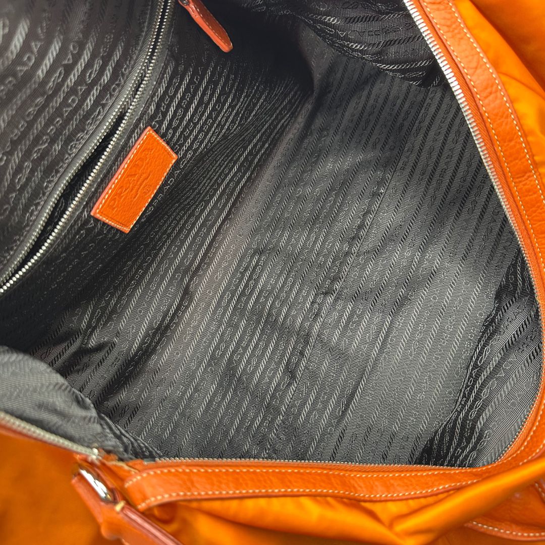 interno Borsone Prada in nylon arancione con finiture in pelle tono su tono e parti metalliche argentate; munita di doppi manici stondati e una tracolla leggermente regolabile, di lusso, originale, ottime condizioni, usata. 
