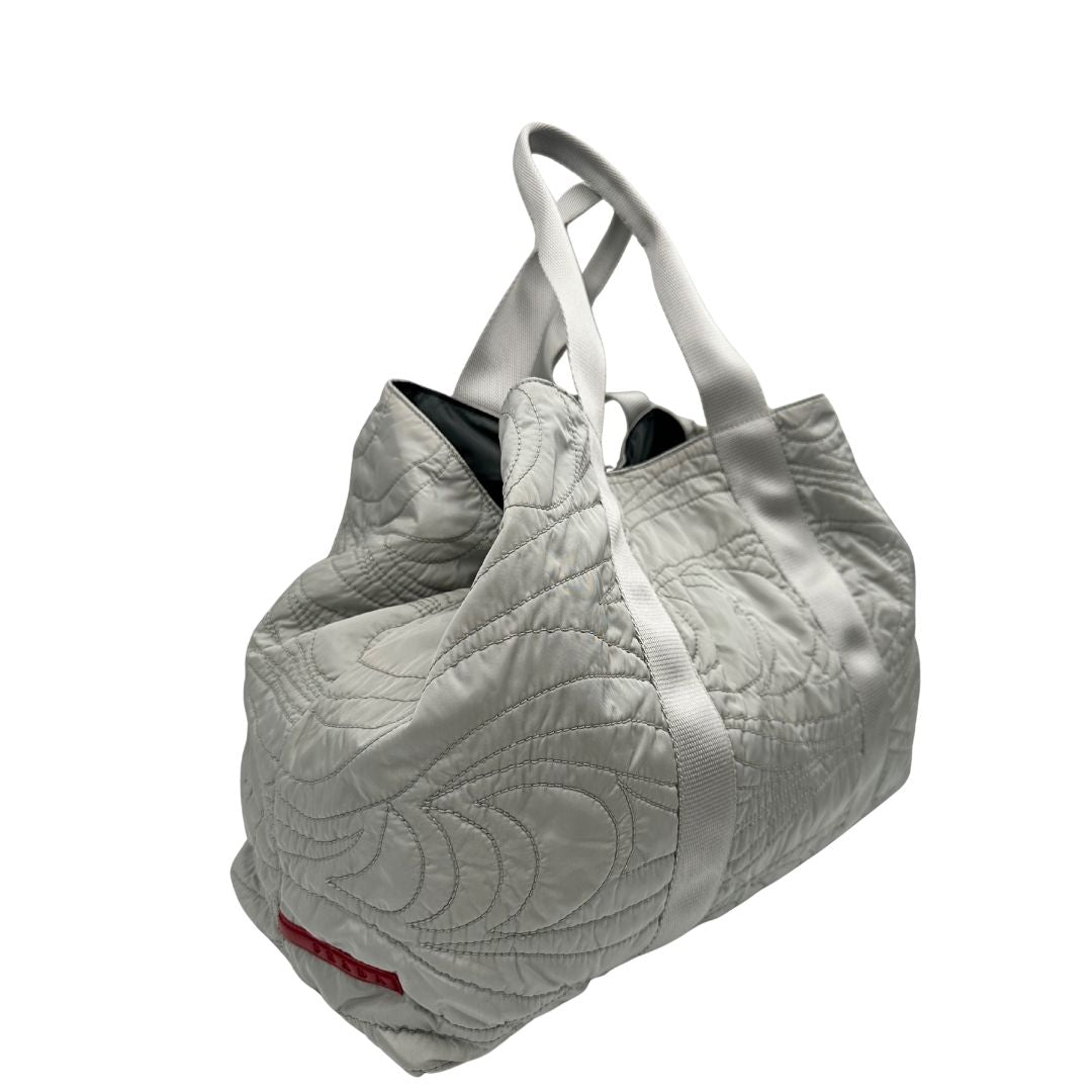 lato Borsa Prada in nylon grigio trapuntato con motivo ondulato, munita di doppi manici in tessuto tono su tono; indossabile a spalla, di lusso, originale, ottime condizioni. 