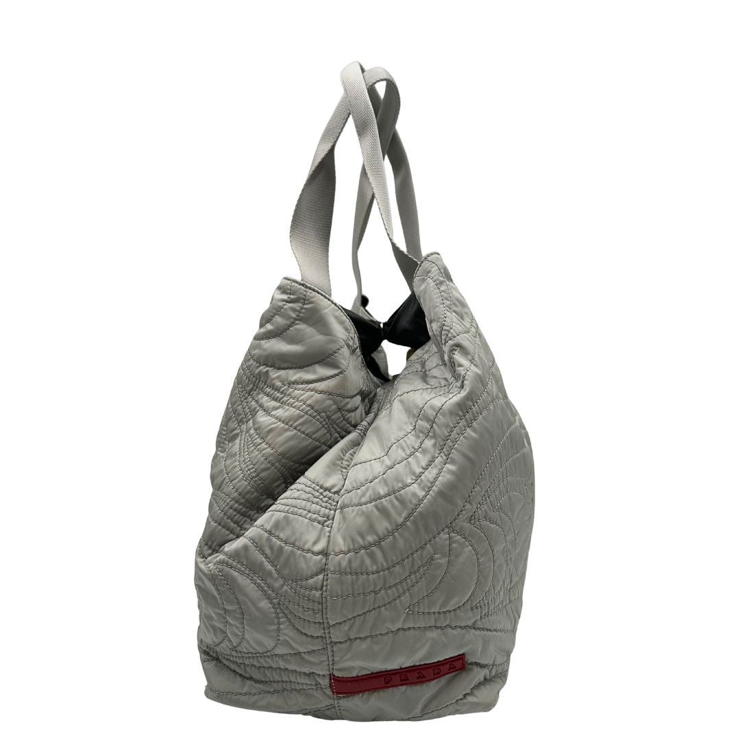 lato Borsa Prada in nylon grigio trapuntato con motivo ondulato, munita di doppi manici in tessuto tono su tono; indossabile a spalla, di lusso, originale, ottime condizioni. 