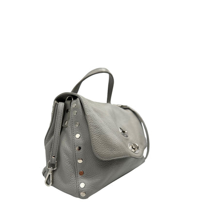 Laterale sinistro di una borsa Zanellato in pelle martellata grigio chiaro, parti con metalliche argentate; munita di un manico singolo, tracolla amovibile e regolabile. Completa di dustbag.