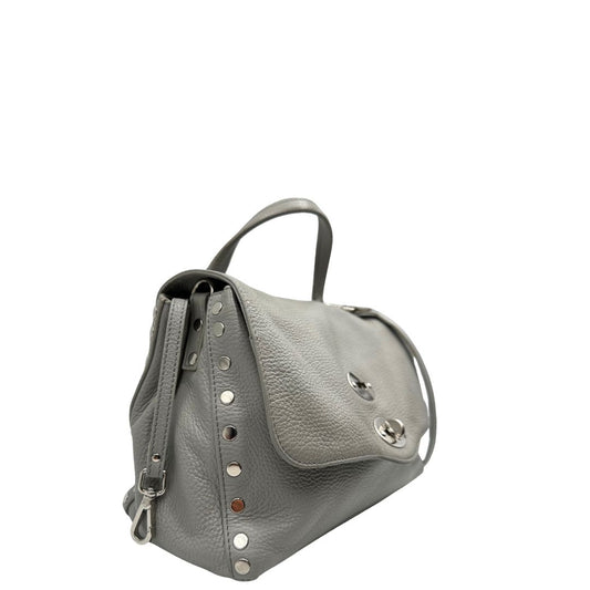 Laterale sinistro di una borsa Zanellato in pelle martellata grigio chiaro, parti con metalliche argentate; munita di un manico singolo, tracolla amovibile e regolabile. Completa di dustbag.