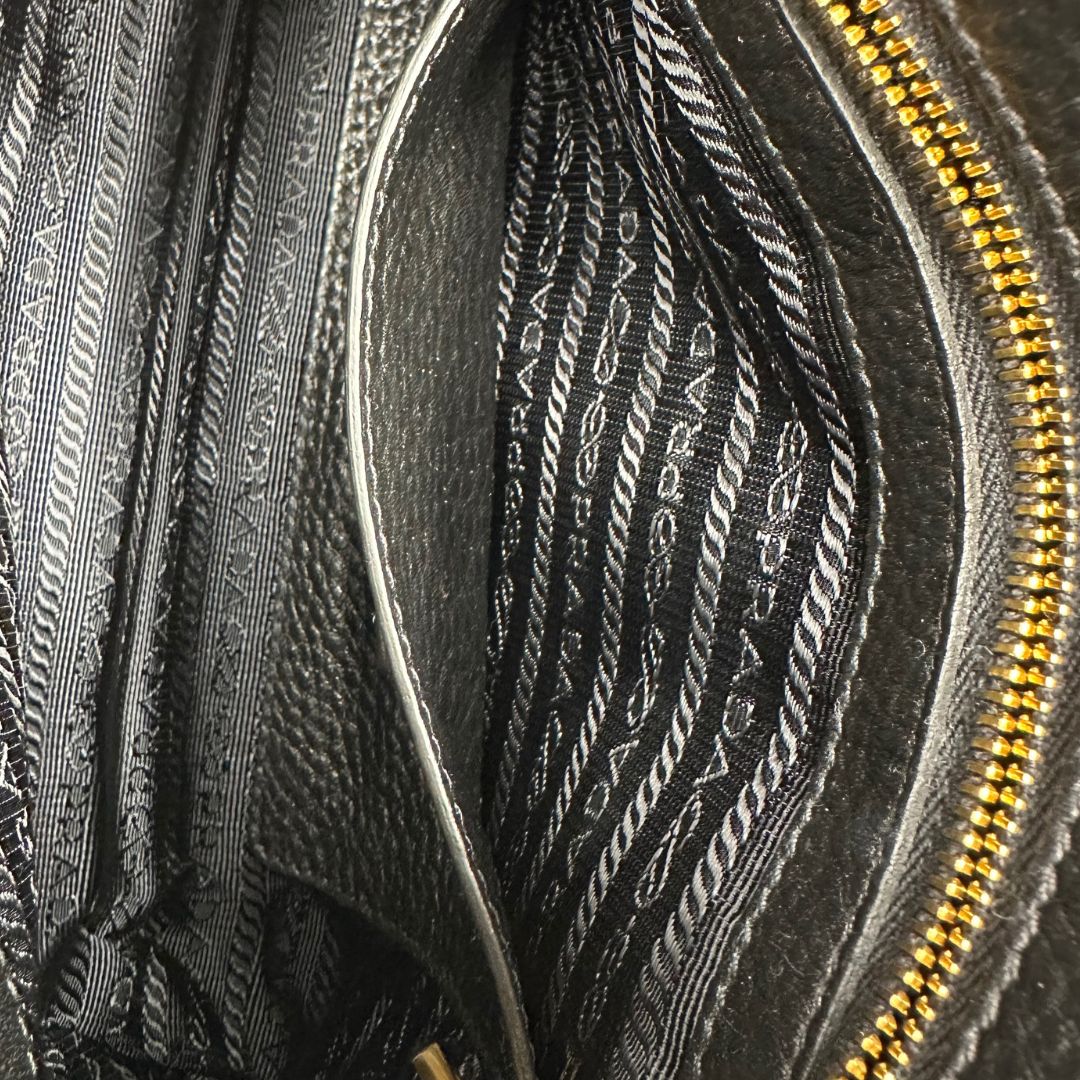 interno Borsa Prada in pelle martellata nera con parti metalliche dorate; munita di una tracolla amovibile e regolabile, da portare a mano, a spalla o a tracolla. Completa di dustbag, di lusso, originale, eccellenti condizioni, usata. 